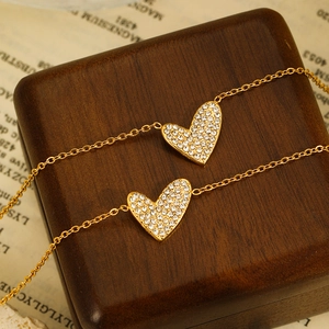 Detailed close-up of golden stainless steel bracelet with heart-shaped zircon charms