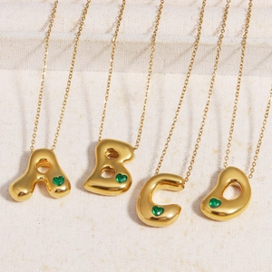 Detail of 18k gold plated bubble letter A B C D pendants with green heart stones