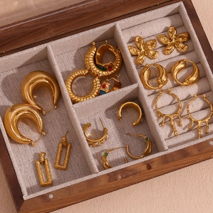 Close-up of vintage 18K gold plated lava earrings and floral studs in a wooden box