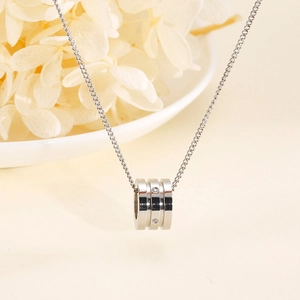 Detail of silver cylinder necklace pendant featuring three tiers and sparkling crystals