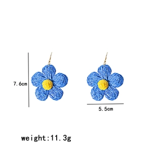 Detailed view of raffia flower earring with blue petals and 7.6cm x 5.5cm dimensions
