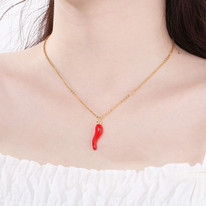 Close-up of a model wearing a gold necklace with a creative red chili pepper pendant