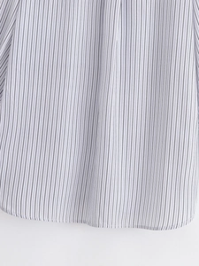 Dettaglio dell'orlo curvo e delle cuciture precise sulla camicia a righe sottili