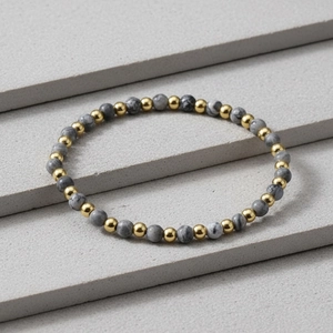 Detail of 4mm faceted amazonite stones and gold plated beads on a grey stone display