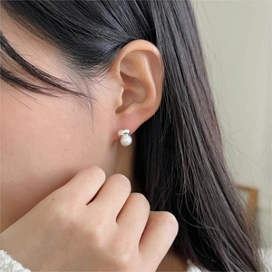 Close-up of minimalist silver drop earrings featuring elegant round white pearls on a model