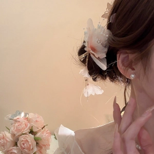 Dettaglio fermaglio per capelli con fiori di tulle, perle e nappe su una modella
