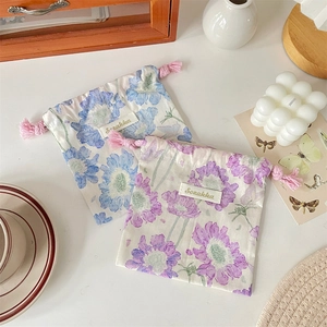 Détail de pochettes à cordon fleuries avec étiquettes tissées et texture coton