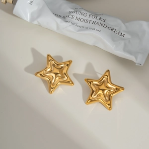 Détail macro de boucles d'oreilles étoiles dorées brillantes avec surface polie en 3D