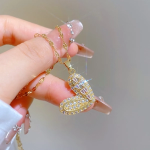 Macro view of gold plated heart pendant with pavé set crystals on a thin water wave chain