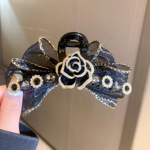 Gros plan sur la pince à cheveux camélia noir avec strass et nœud en tulle fin