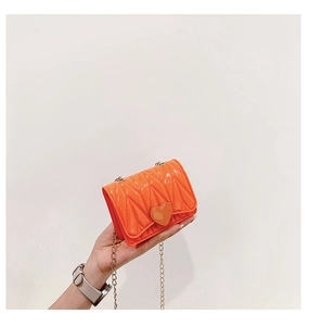 Detail of orange quilted mini silicone bag featuring a heart clasp and gold metal chain