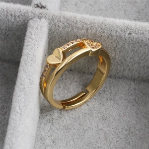 Adjustable gold heart ring with cubic zirconia stones on a gray jewelry box