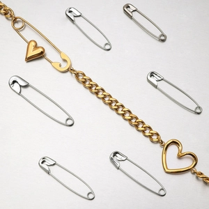 Detail of 18K gold paperclip necklace featuring heart charms and freshwater pearls