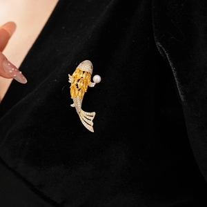 Macro view of koi carp brooch with yellow gemstones and pearl on black velvet