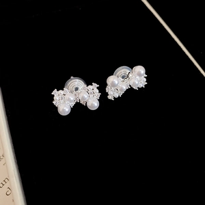 Détail de boucles d'oreilles clips en perles et zircons avec coussinet sur velours noir