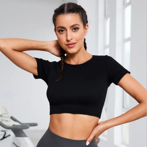 Slim fit black ribbed crop top for yoga and fitness training in a bright gym setting