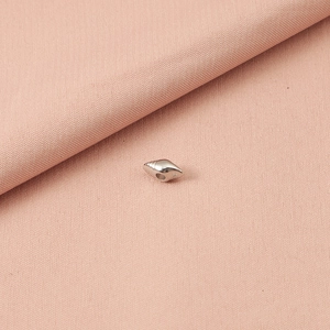 Gedetailleerde close-up van een zilveren zeester hanger op zachte roze getextureerde stof