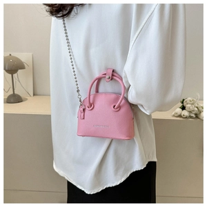 Close-up of pink mini shell bag with silver bead chain strap on model with white top