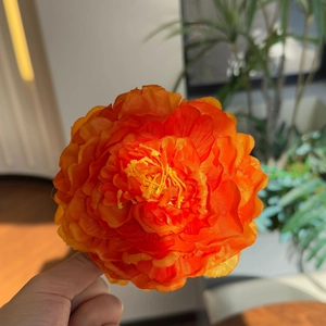 Macro detail of realistic orange peony hair clip with layered silk petals and yellow stamens