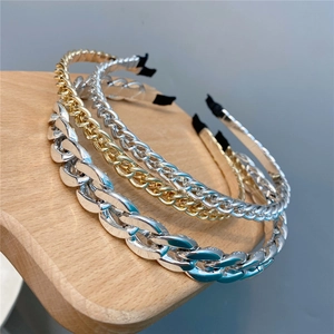 Detailed close-up of metallic chain headbands on a wooden display stand