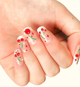 Détail de faux ongles French avec motifs cerises rouges et étoiles scintillantes
