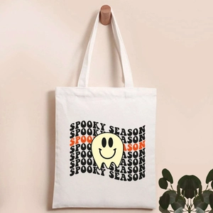 Detail of hanging white canvas tote bag with Spooky Season text and ghost print