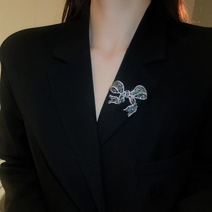 Bow brooch with purple and green crystals pinned on a professional black blazer lapel