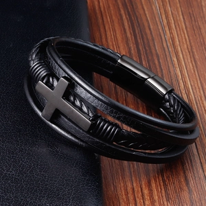 Close-up of men's braided black leather bracelet with metal cross detail and magnetic clasp