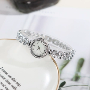 Silver jewelry watch with rhinestone bracelet on a decorative ceramic plate