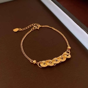 Detailed view of a gold chain bracelet with five interlocking wavy rings and heart charm
