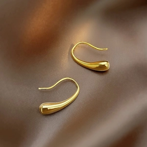 Elegant gold teardrop hook earrings with polished metallic finish on silk fabric