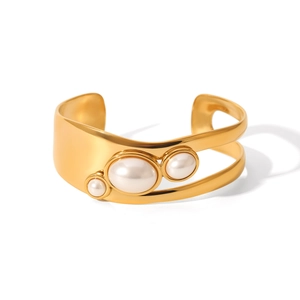 Detail of wide gold hollow cuff bracelet with three gradient pearls on white background