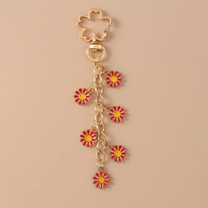 Detail of gold metal keychain featuring several red daisy and cherry blossom pendants