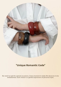Close-up of thick resin bangles in red, amber, and black with a smooth polished finish