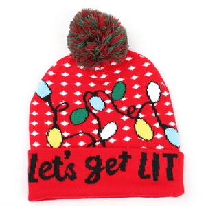 Close-up of 'let's get LIT' text on a red Christmas pom-pom beanie with snowflake motifs