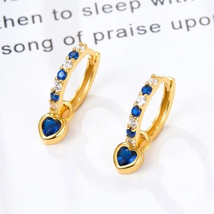 Macro shot of gold heart earrings with blue zircons and sparkling crystals