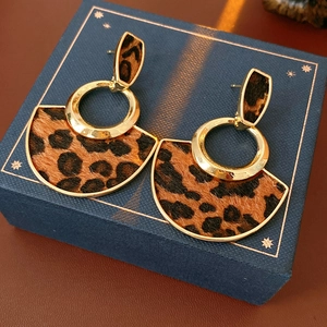 Detail of fan-shaped leopard print earrings placed on a deep blue velvet jewelry box