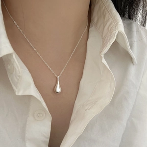 Minimalist sterling silver necklace featuring a polished teardrop pendant on a model