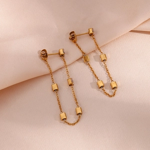 Detailed view of gold chain earrings with square metal pendants and zircon stones
