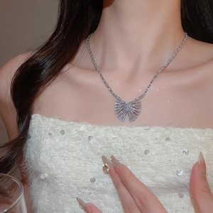 Collier élégant avec pendentif papillon en zircon porté par un mannequin en robe blanche