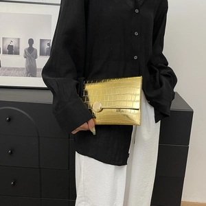 Close-up of golden stone-textured envelope clutch bag with metal round buckle