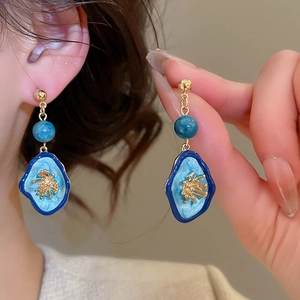 Gros plan détaillé de boucles d'oreilles vintage en émail bleu avec accents dorés