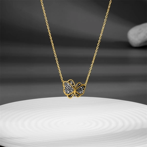 Detail of a golden butterfly pendant with black crystals on a white textured plate