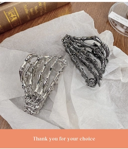 Detailed view of gothic silver and black skull hand hair claws on textured background