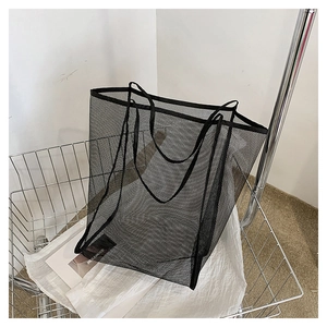 Dettaglio di una borsa shopping in rete nera con spalline ampie in un carrello spesa