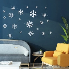 Detailed view of silver reflective snowflake wall decals on a dark blue home interior wall