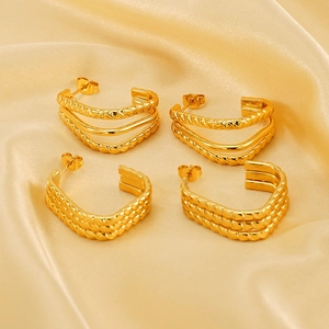 Irregular gold multilayer C-shape earrings on silk background in a professional shot