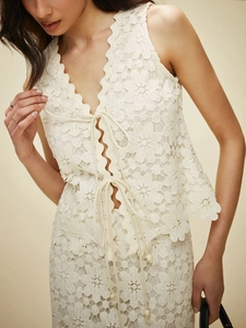 Gros plan sur le gilet en dentelle blanche avec lacets et motifs floraux sophistiqués
