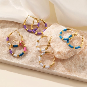 Créoles en émail coloré plaquées or 18 carats sur fond de marbre et de soie