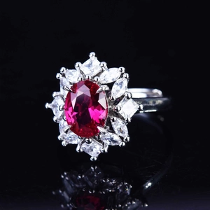 Macro view of luxury oval red gemstone ring with floral diamond halo and silver band